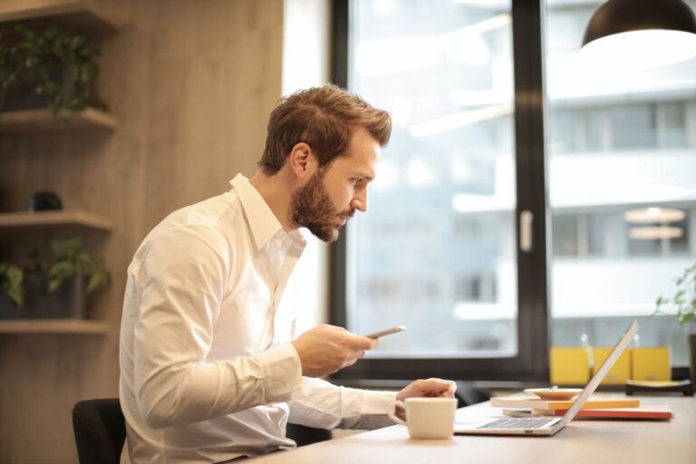 Manager di un'azienda che con telefono e computer sta per chiamare l'assistenza tecnica.