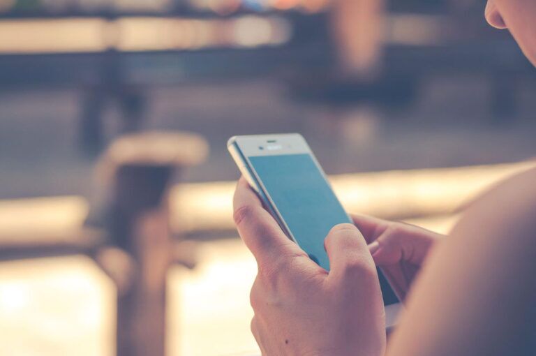 Ragazza guarda un app sul suo smartphone in un villaggio.
