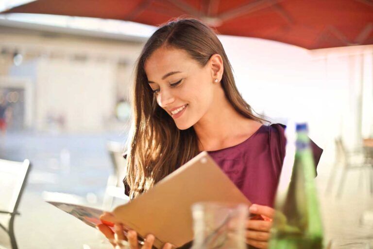 Ragazza sorride mentre legge il menu del ristorante.