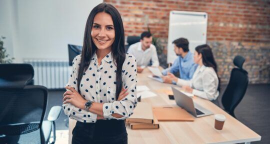 donna al lavoro in ufficio e colleghi che leggono articolo su CRM gartner 2026
