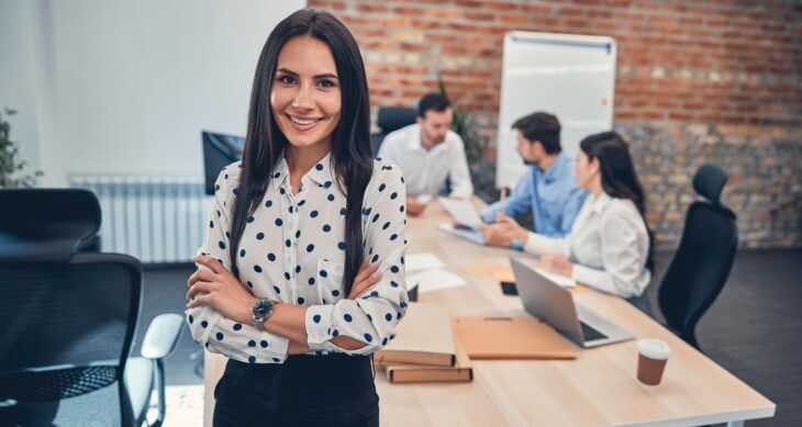 donna al lavoro in ufficio e colleghi che leggono articolo su CRM gartner 2026