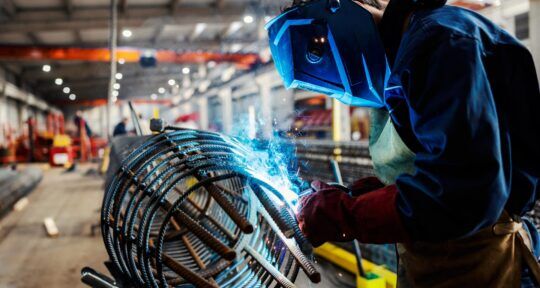 Blog lavorazione su commessa Operaio con visore che sta saldando all'interno di un reparto di fabbrica