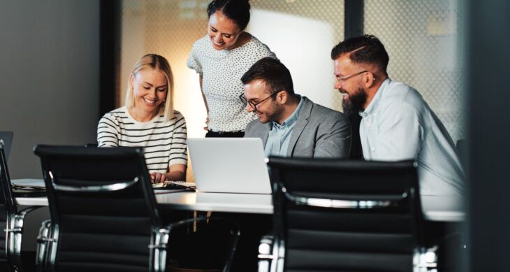 industrializzazione del prodotto due donne e due uomini in ufficio che guardano lo schermo di un portatile