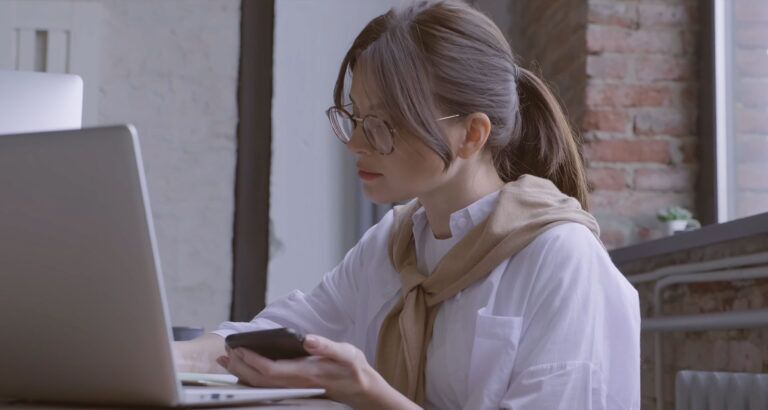 Ragazza lavora nel back office dell'hotel con telefono e computer.