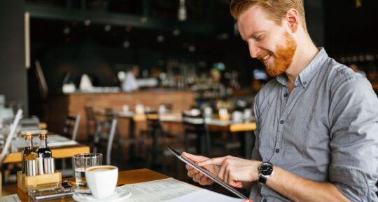 Ristoratore sorride guardando dati di Business Intelligence su un tablet