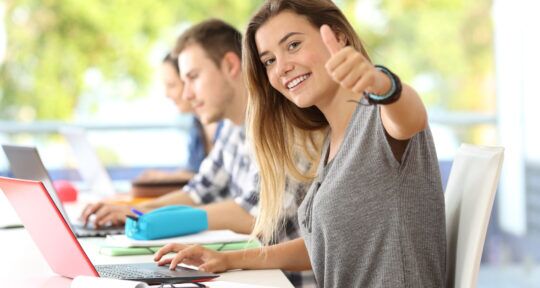 Ragazza sorride davanti a computer in aula