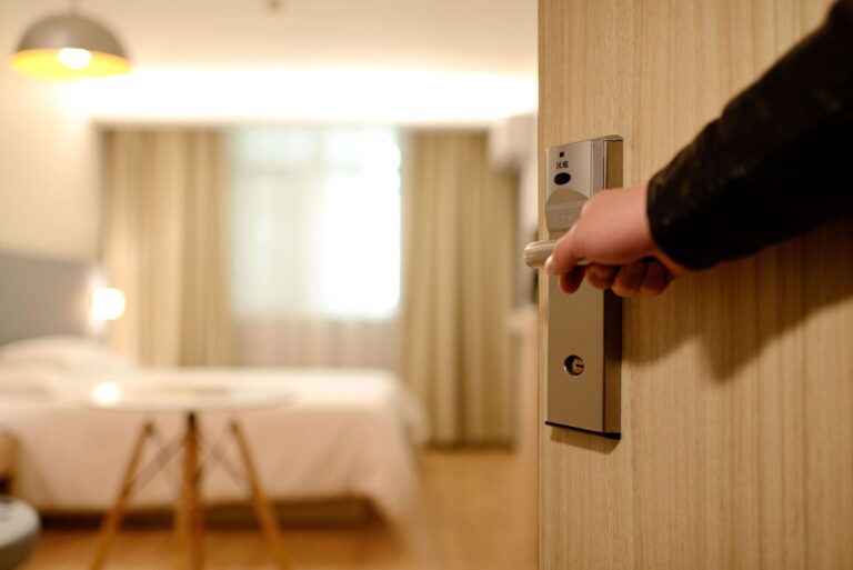 Mano che apre la porta di una camera d'hotel.
