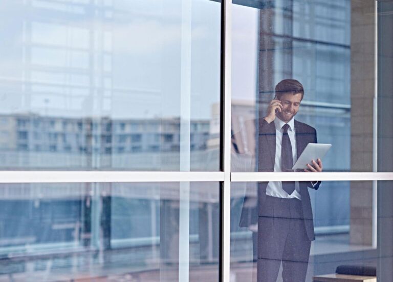 Manager guarda il tablet e risponde al telefono mentre sorride.