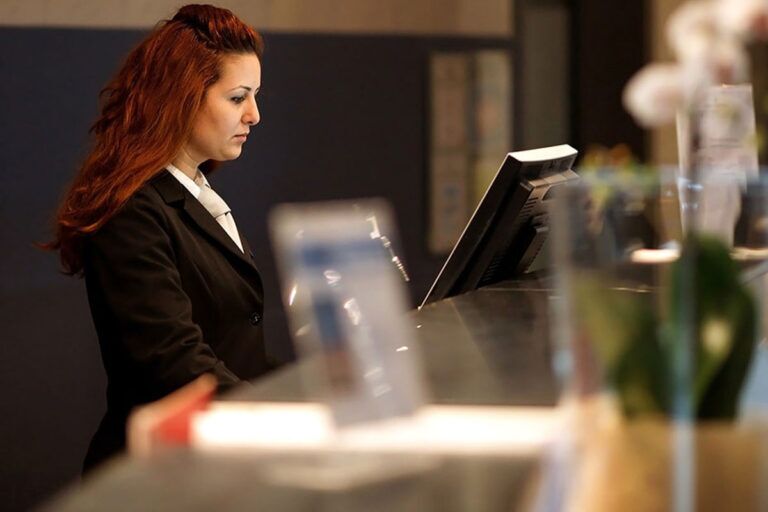 Receptionist usa il PMS sul computer dell'hotel.