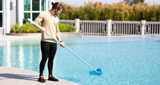 Addetto all'housekeeping e manutenzione pulisce una piscina