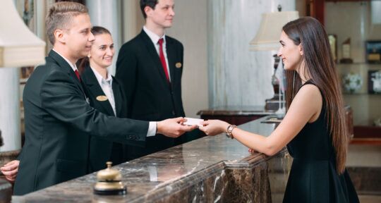 day-use en hoteles Recepcionista de hotel entregando una llave magnética a un huésped