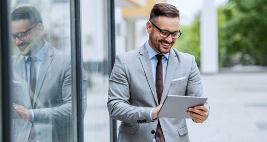 Cover blog Customer Loyalty proprietario di un hotel sorride, è fuori dall'hotel e sta guardando KPI