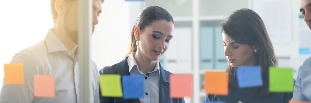 PRINCE2 nell’implementazione software, simboli informatici, 3 colleghi lavorano al progetto con post it alla parete