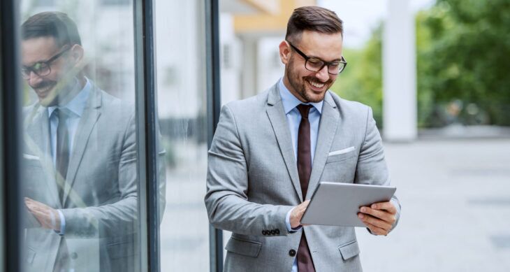 Cover blog Customer Loyalty proprietario di un hotel sorride, è fuori dall'hotel e sta guardando KPI