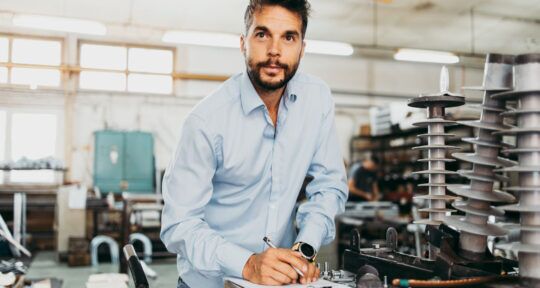 Cover blog Capacity Plan uomo in camicia con penna in mano in un reparto produttivo